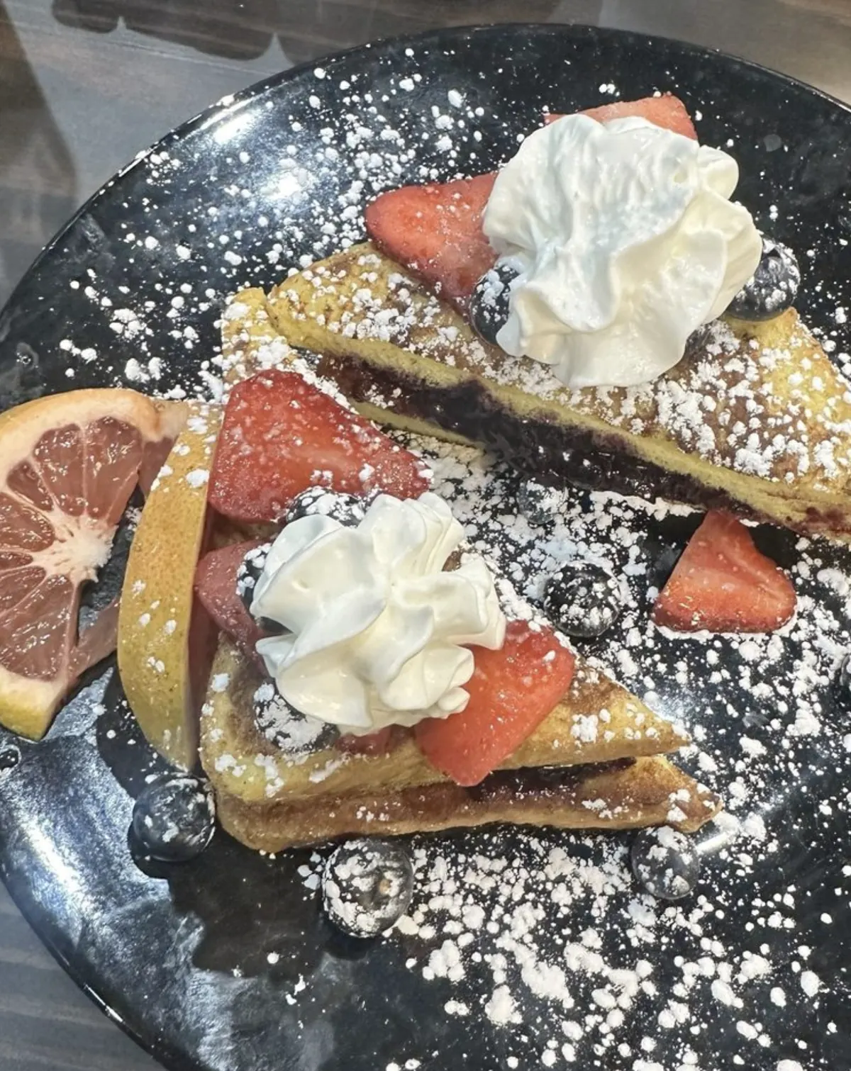 French toast with strawberries, berries, whipped cream, and powdered sugar